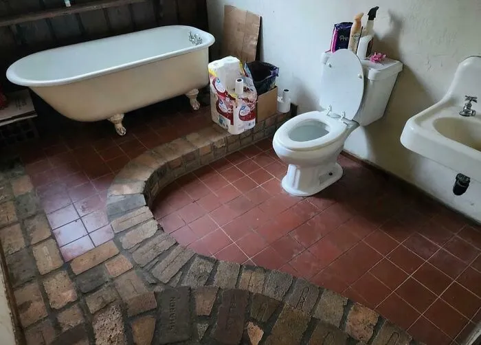 Unusual bathroom layout featuring a raised brick platform for the toilet, highlighting strange house designs.