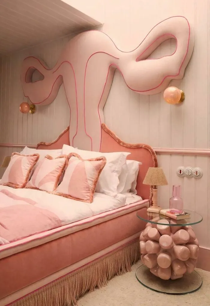 A pink bedroom with a uterus-shaped headboard showing unusual houses design choices