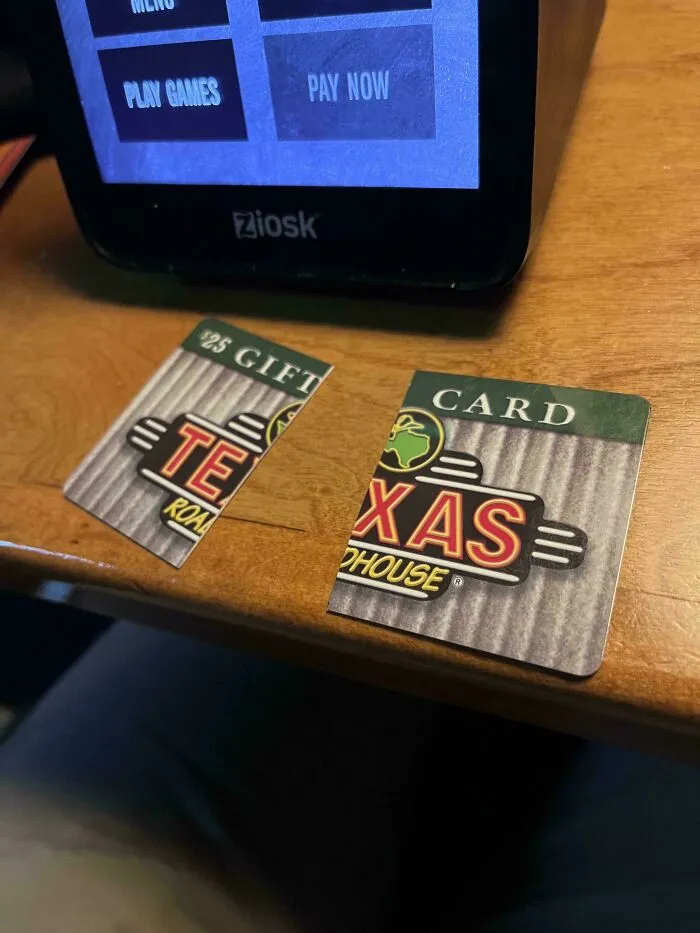 Broken Texas Roadhouse gift card found during dumpster diving on wooden table