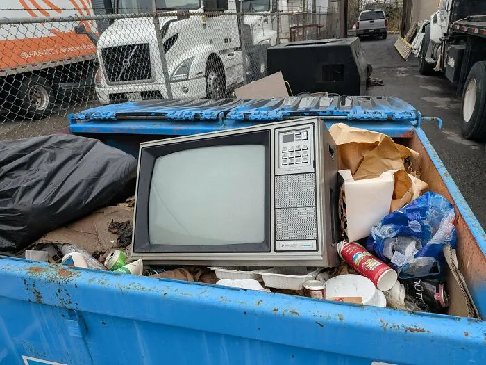Old vintage television discarded in dumpster during dumpster diving