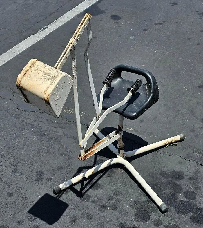 Rusty exercise machine with black seat found dumpster diving