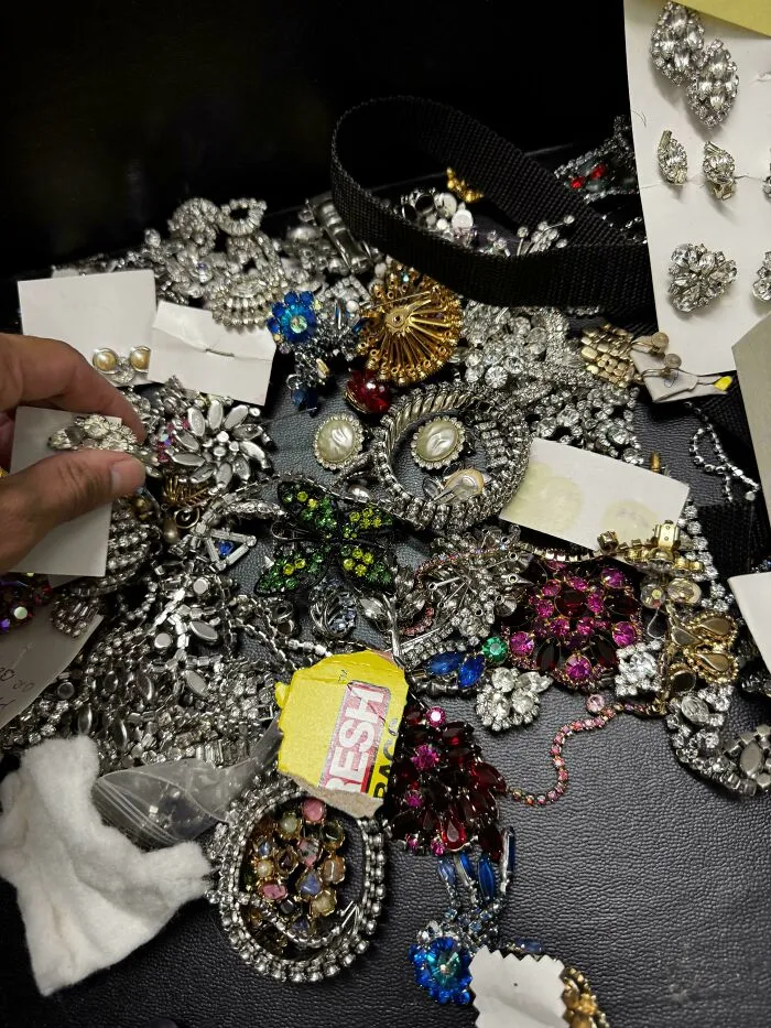 Assorted vintage costume jewelry found dumpster diving with person holding a brooch