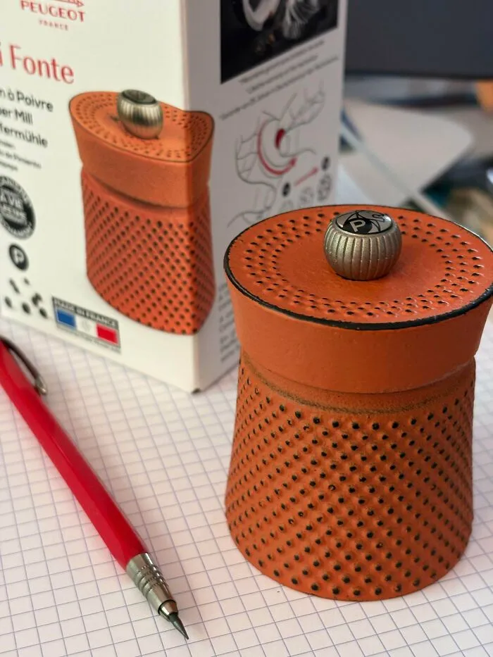 An orange textured Peugeot pepper mill representing high quality old products for kitchen use.