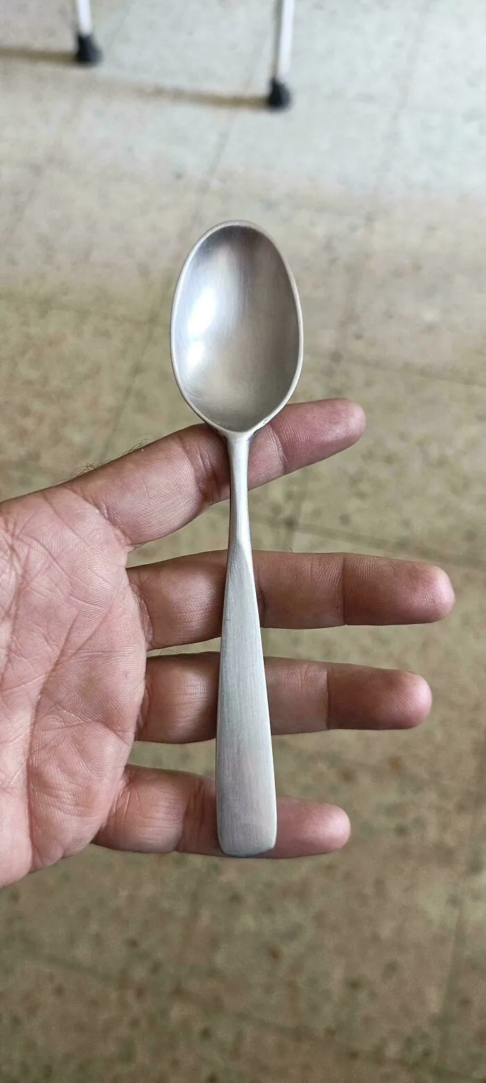 Simple metal spoon held in hand, showcasing simple old products that remain functional after decades of daily use.