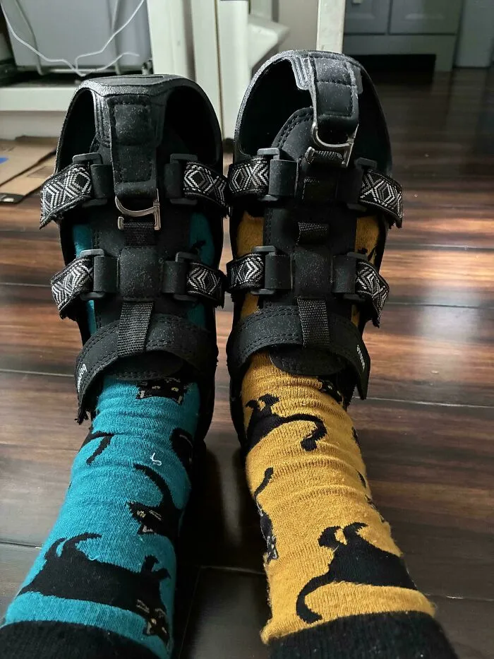 Feet wearing cat-patterned socks and sturdy sandals, showcasing old products that remain functional for years.