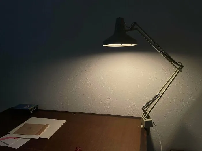 A vintage desk lamp glowing over a wooden table, representing durable old products built for long-term use.