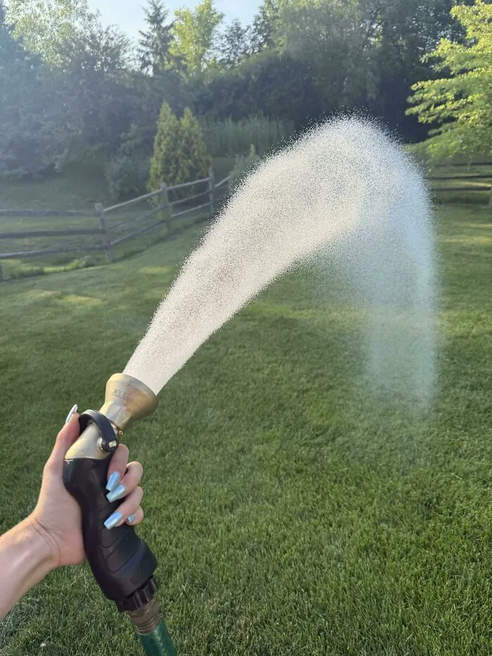 Hand spraying water from a durable hose nozzle, representing reliable old products.