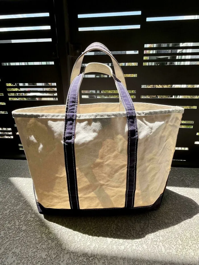 Durable canvas tote bag with navy blue handles resting on a surface, among old products still in use.