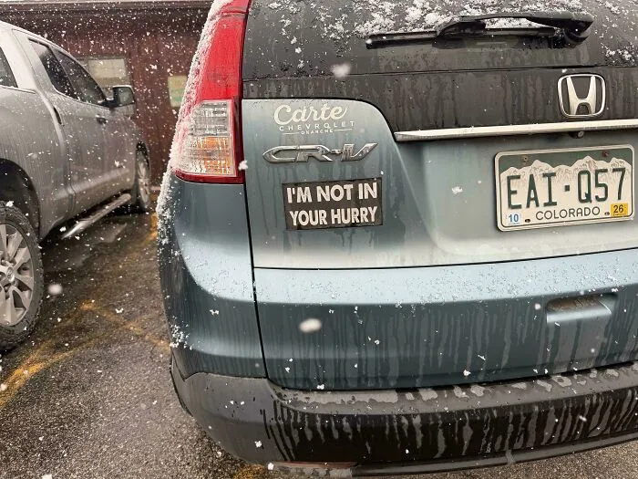 A bumper sticker on a blue car that reads I am not in your hurry.