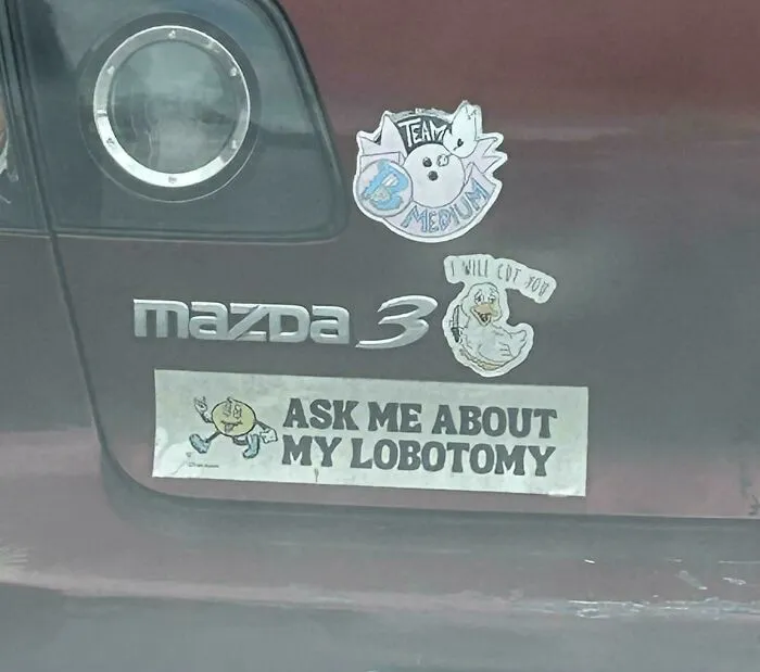 Back of a car with a decal reading Ask me about my lobotomy, among wild bumper stickers.