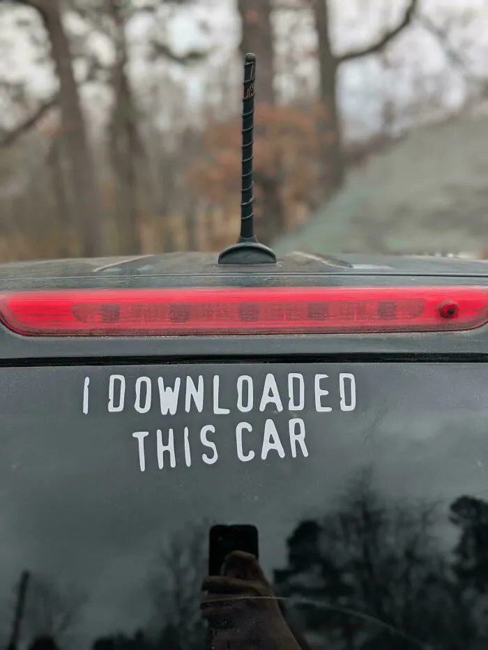 Decal bumper stickers on a car rear windshield saying I downloaded this car.