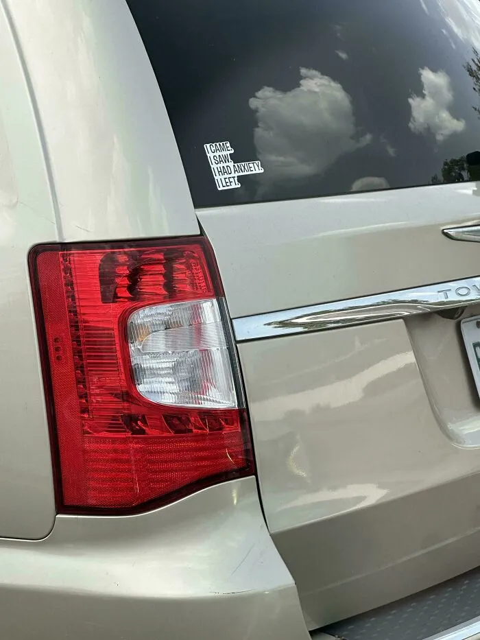 Small relatable bumper stickers about anxiety on a car window.