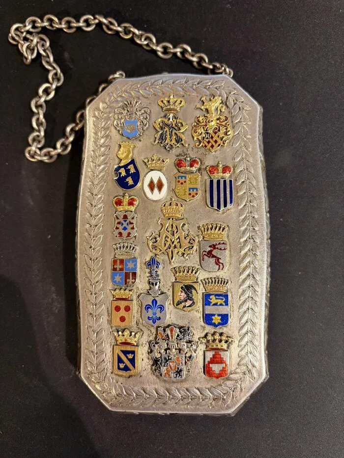An ornate silver purse adorned with colorful royal crests, representing old treasures.
