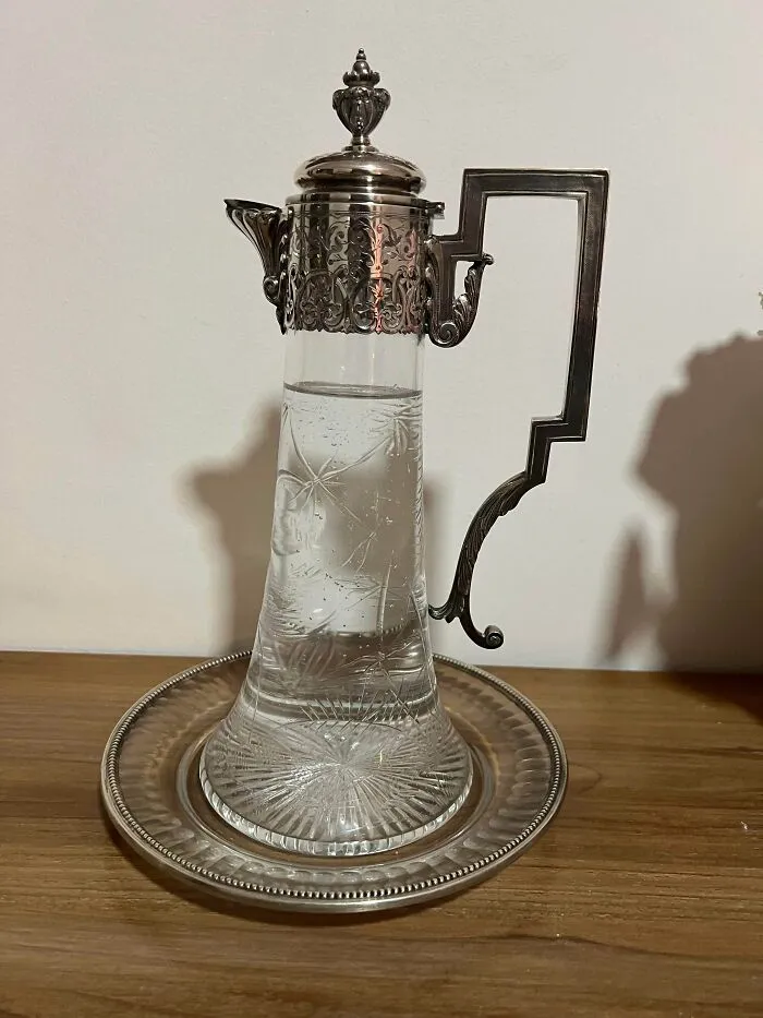 Antique lovers treasure vintage silver and crystal claret pitcher with intricate metallic lid and decorative handle.