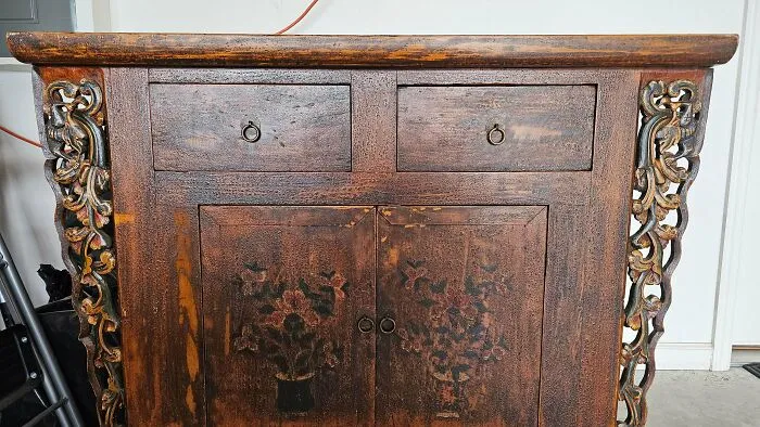 An antique wooden cabinet with hand-painted floral details, an example of old treasures.