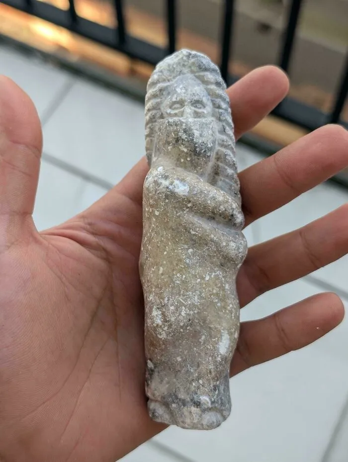 A hand holding a carved stone figurine, one of many old treasures found by collectors.