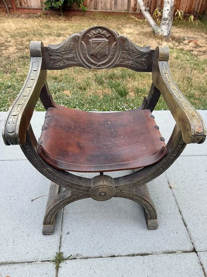 An ornate carved wooden chair with a leather seat, showcasing old treasures for antique lovers