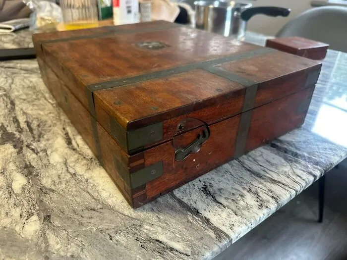 Vintage wooden writing slope with brass fittings, showcasing old treasures found by antique lovers.