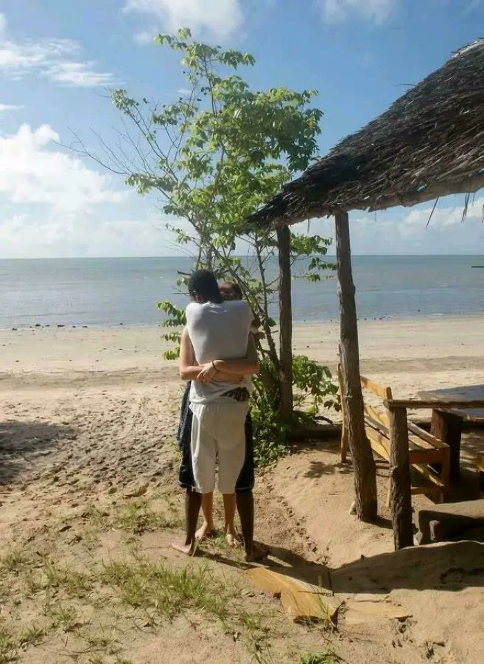 Beach scene where a couple's embrace is hidden by a tree, creating a visual illusion
