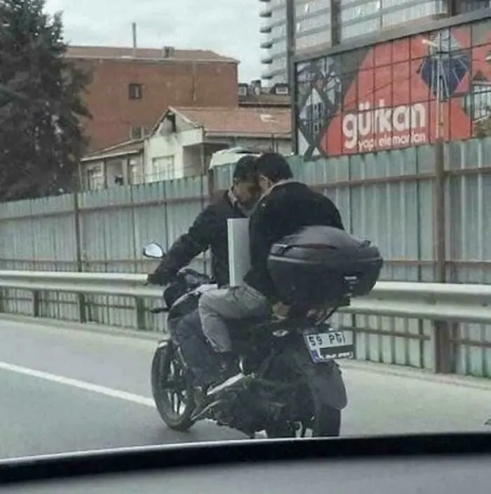 Two men on a motorcycle create visual confusion with their positioning on the road
