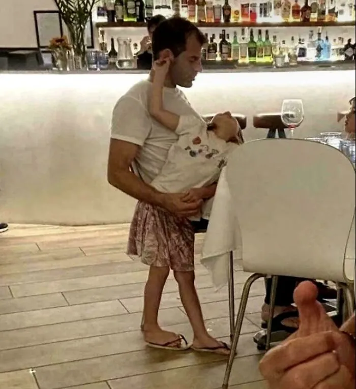 Man holding child looks like child wearing adult skirt due to optical illusion