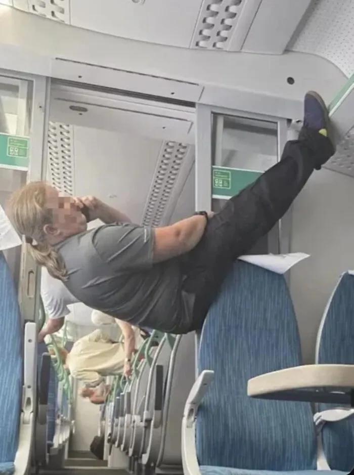 Person appearing to hang sideways on train seats creating visual confusion