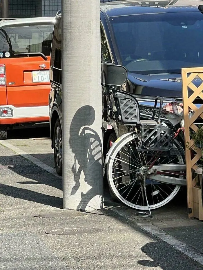 Bicycle shadow on pole creates illusion of an alien figure