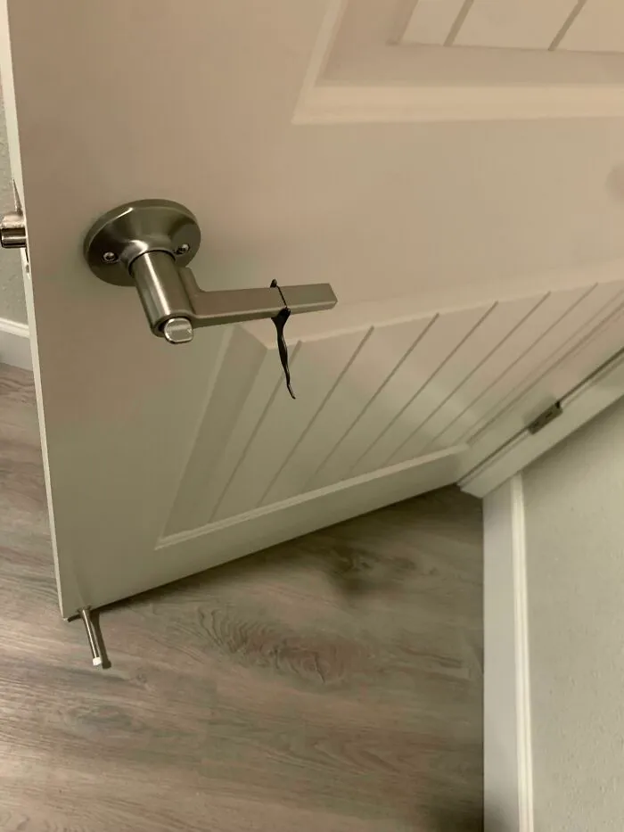 A simple black hair tie wrapped around a silver metal door handle