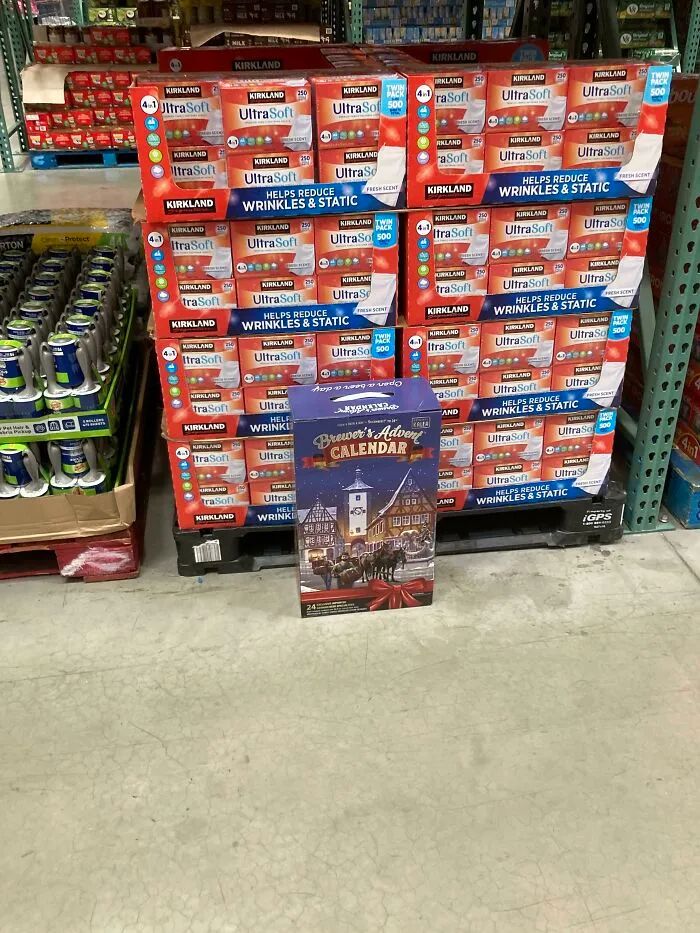 Stack of laundry products in a store with an out-of-place Christmas beer advent calendar, showcasing cute things wives do.