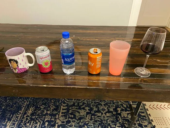 A line of different drinking cups and cans lined up on a table, highlighting unhinged things wives do.