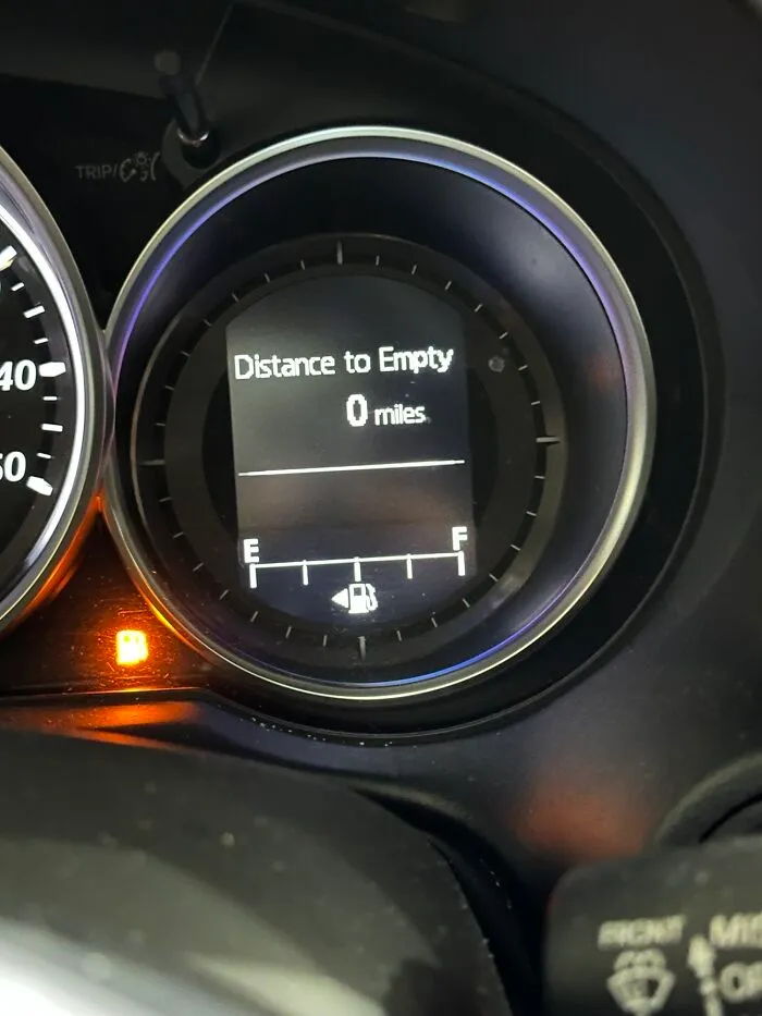 A car dashboard showing zero miles to empty, a funny example of ridiculous things wives do.