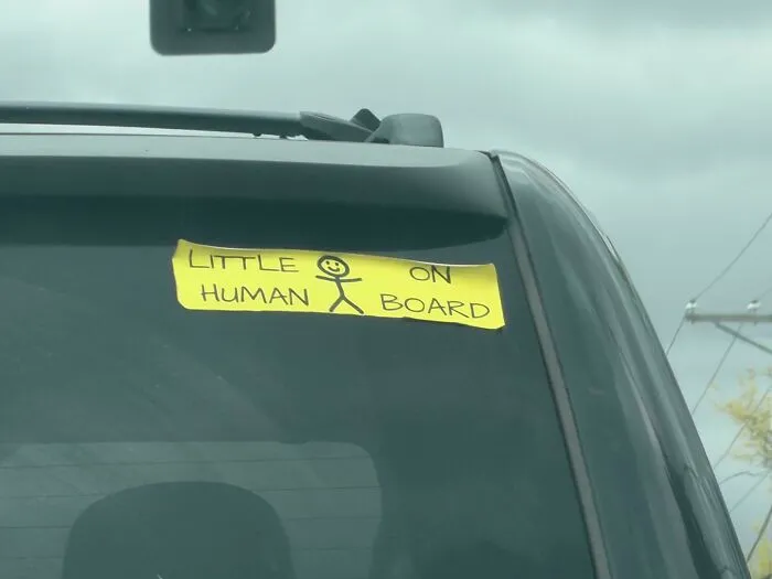 Handmade little human on board bumper sticker on car window, an example of hilarious badly designed signs.