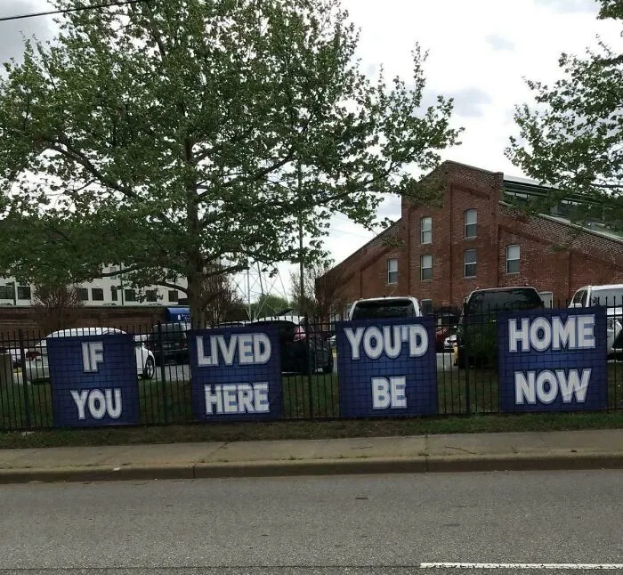 Blue signs on a fence featuring poorly ordered text creating a badly designed sign.