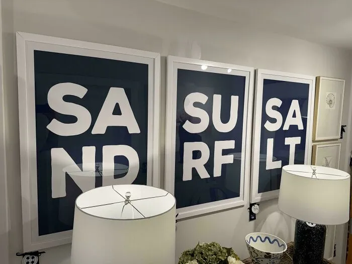 Framed wall art prints displaying badly designed signs with poorly formatted letters spelling sand, surf, and salt.