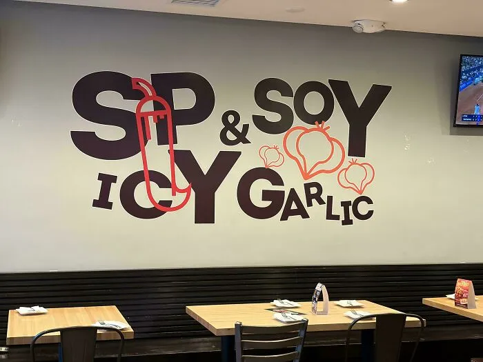 Confusing wall graphic displaying badly designed signs text that mixes spicy soy and icy garlic phrases.