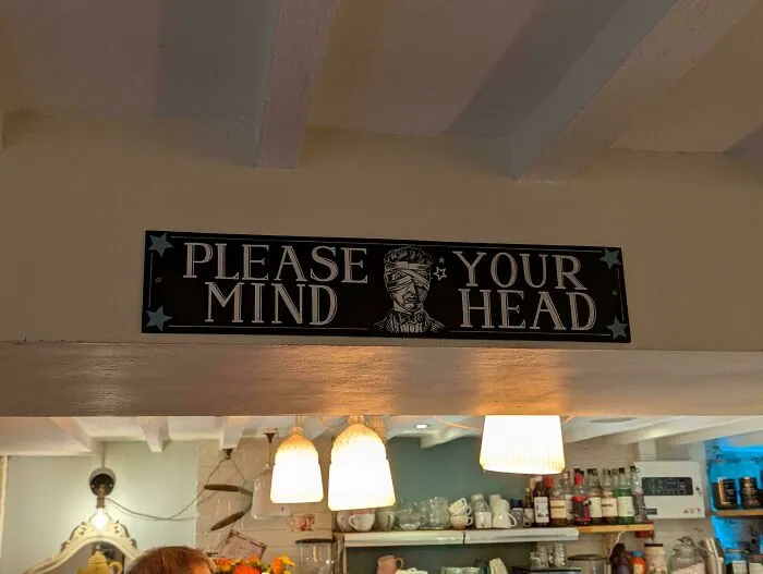 A badly designed sign that reads PLEASE YOUR MIND HEAD with a blindfolded face graphic