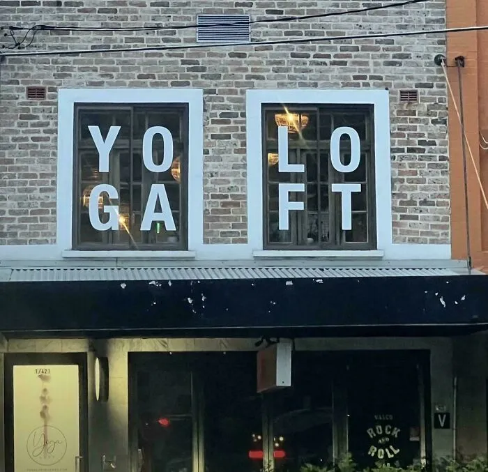 A window sign showing badly designed signs with text reading YOGA LOFT confusingly split across windows.