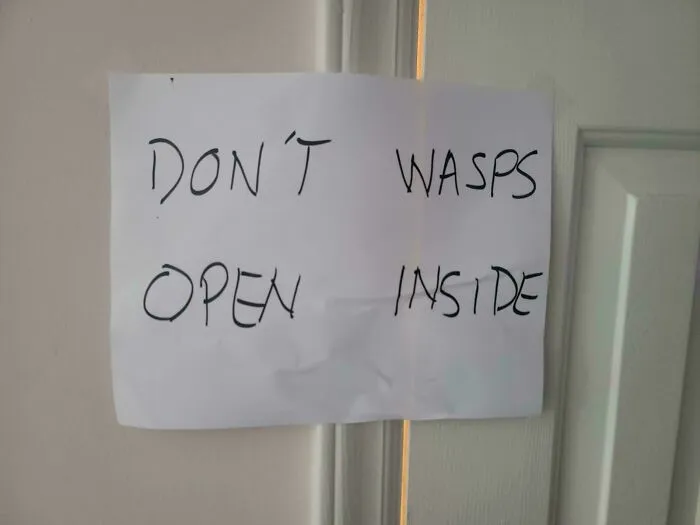 Paper sign with confusing formatting reading DON'T WASPS OPEN INSIDE, a hilarious badly designed sign on a door.