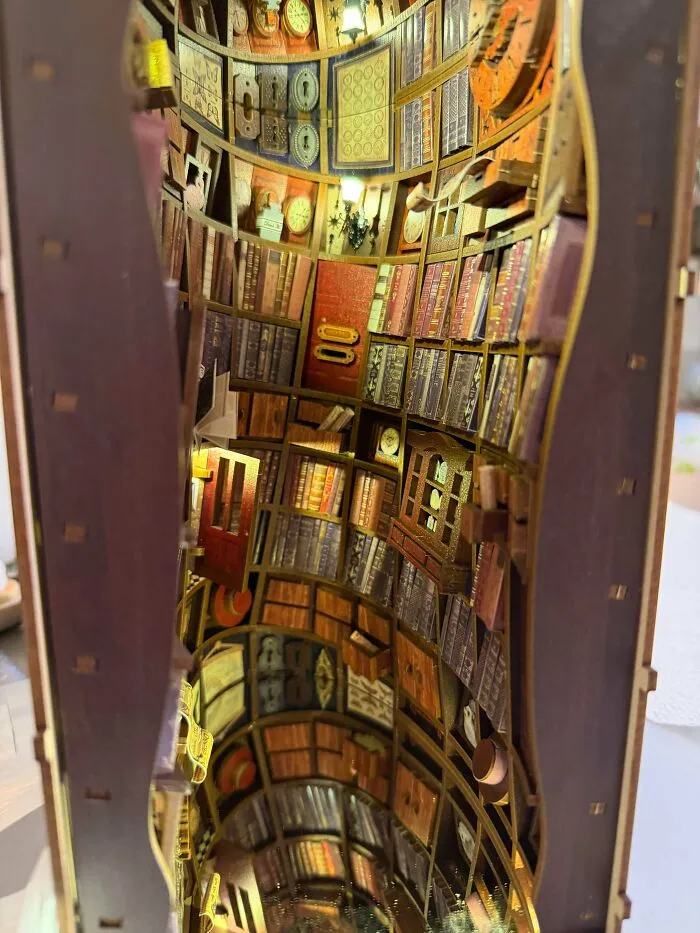 A curved library miniature book nook showing rows of books and warm interior lighting