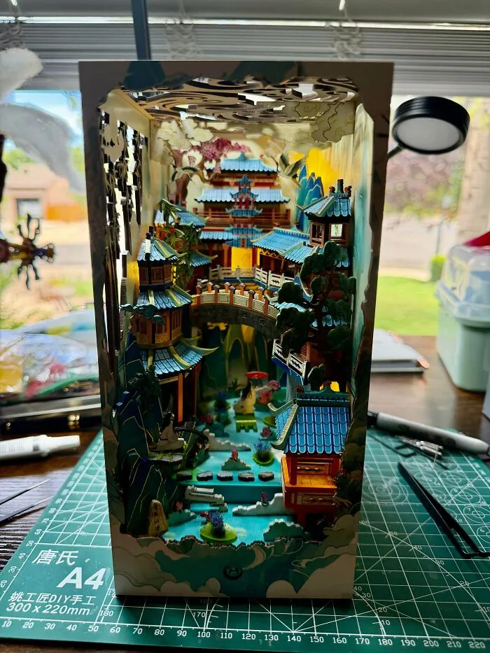 An intricate book nook featuring a Chinese-style palace with bridges and blue rooftops
