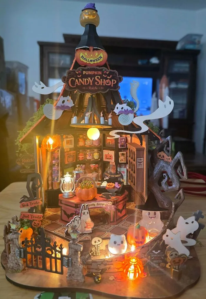 Spooky Halloween pumpkin candy shop book nook featuring friendly paper ghosts and warm lights