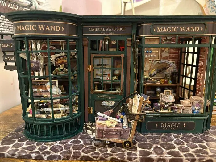 Detailed magic wand shop book nook with tiny shelves and a cart filled with spellbooks