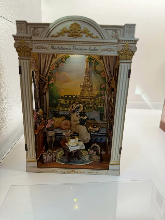 An elegant Parisian book nook featuring a cat reading on a balcony with the Eiffel Tower in the background