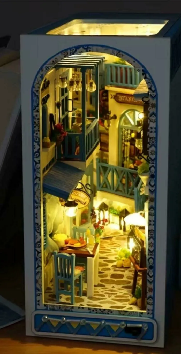 A glowing book nook miniature depicting a cozy Mediterranean street with balconies and dining tables