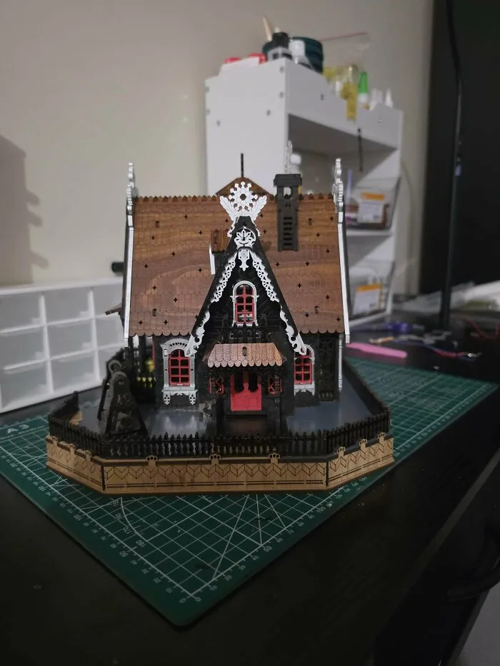 A charming gingerbread style miniature house book nook placed on a green cutting mat.