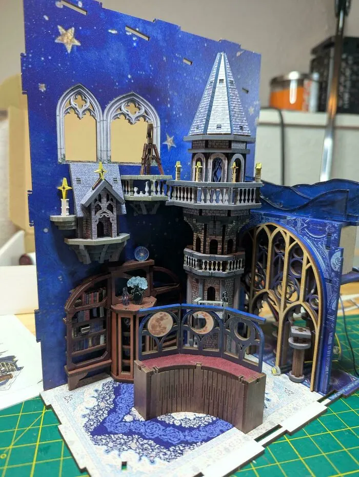 A detailed book nook miniature of an astronomical observatory with a starry night sky backdrop.