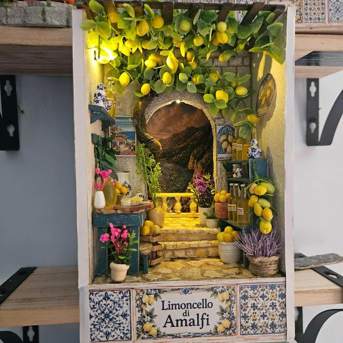 An Amalfi coast themed book nook featuring yellow lemons, shelves of bottles, and a stone archway.