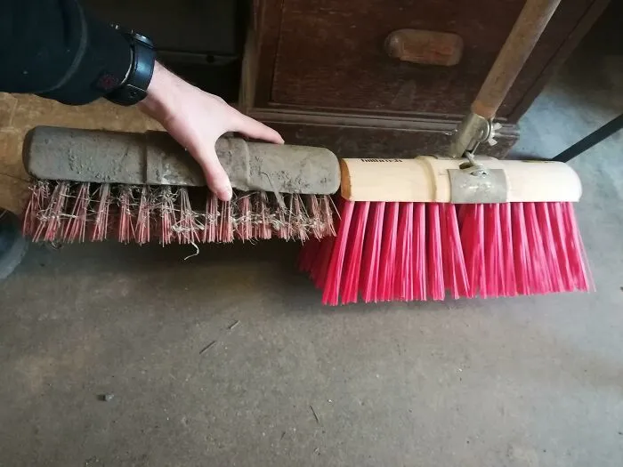 A worn old broom compared to a brand new one showing how time slowly reshapes tools.