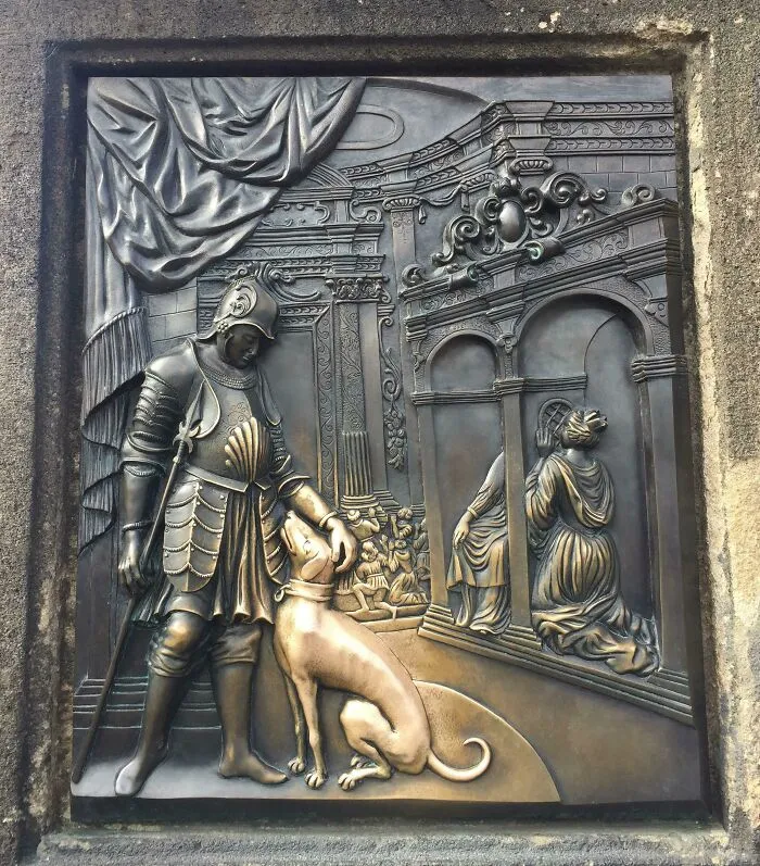 A polished bronze relief plaque showing how time reshapes the surface where people touch it