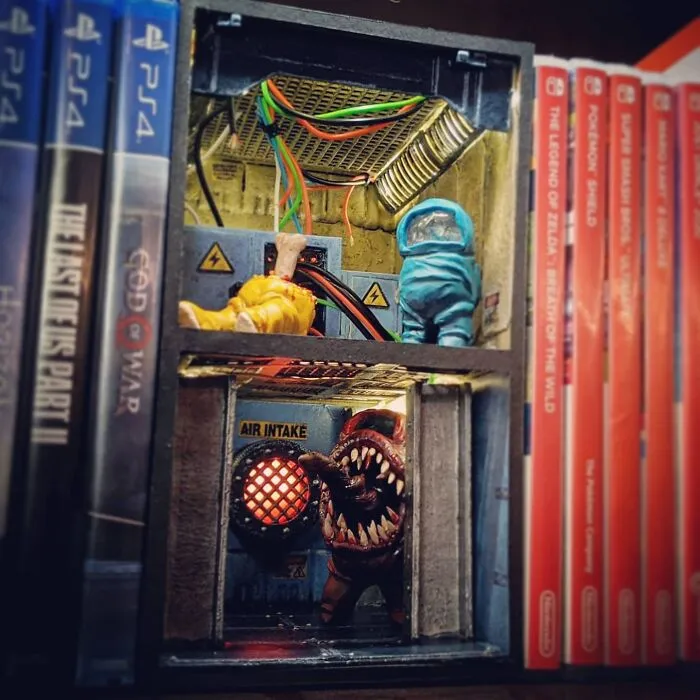 An Among Us themed book nook featuring game characters and an air intake vent, placed between game cases.